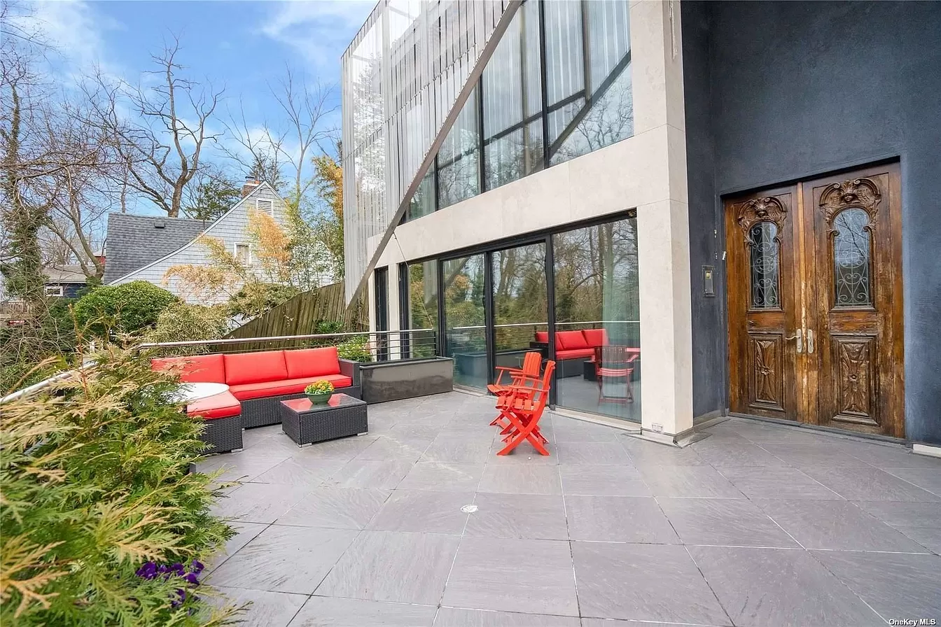person writing in a notebook beside by an iPad, laptop, printed photos, spectacles, and a cup of coffee on a saucer