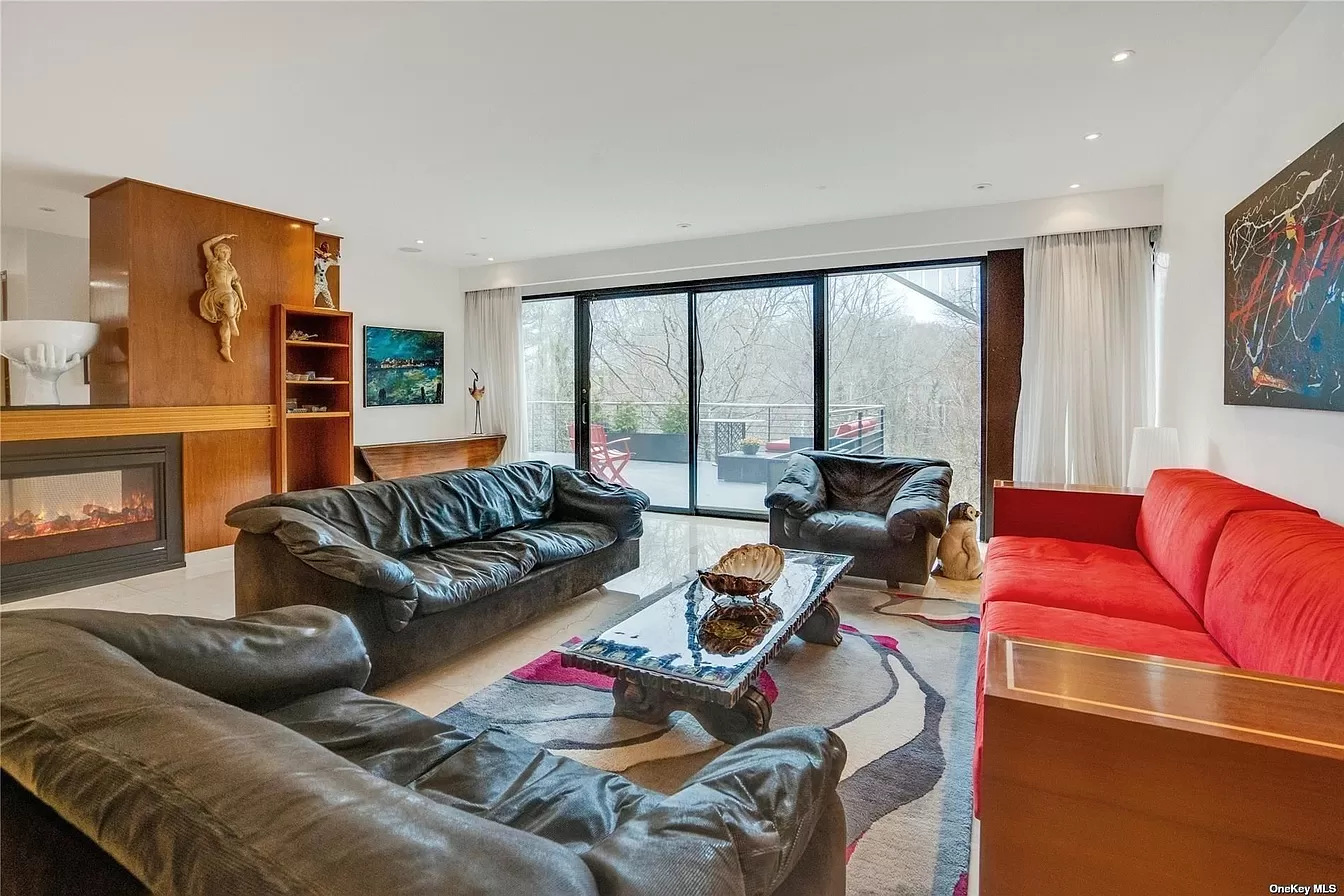 man wearing a black jacket, white shirt, blue jeans, and brown boots, playing a white electric guitar while sitting on an amp