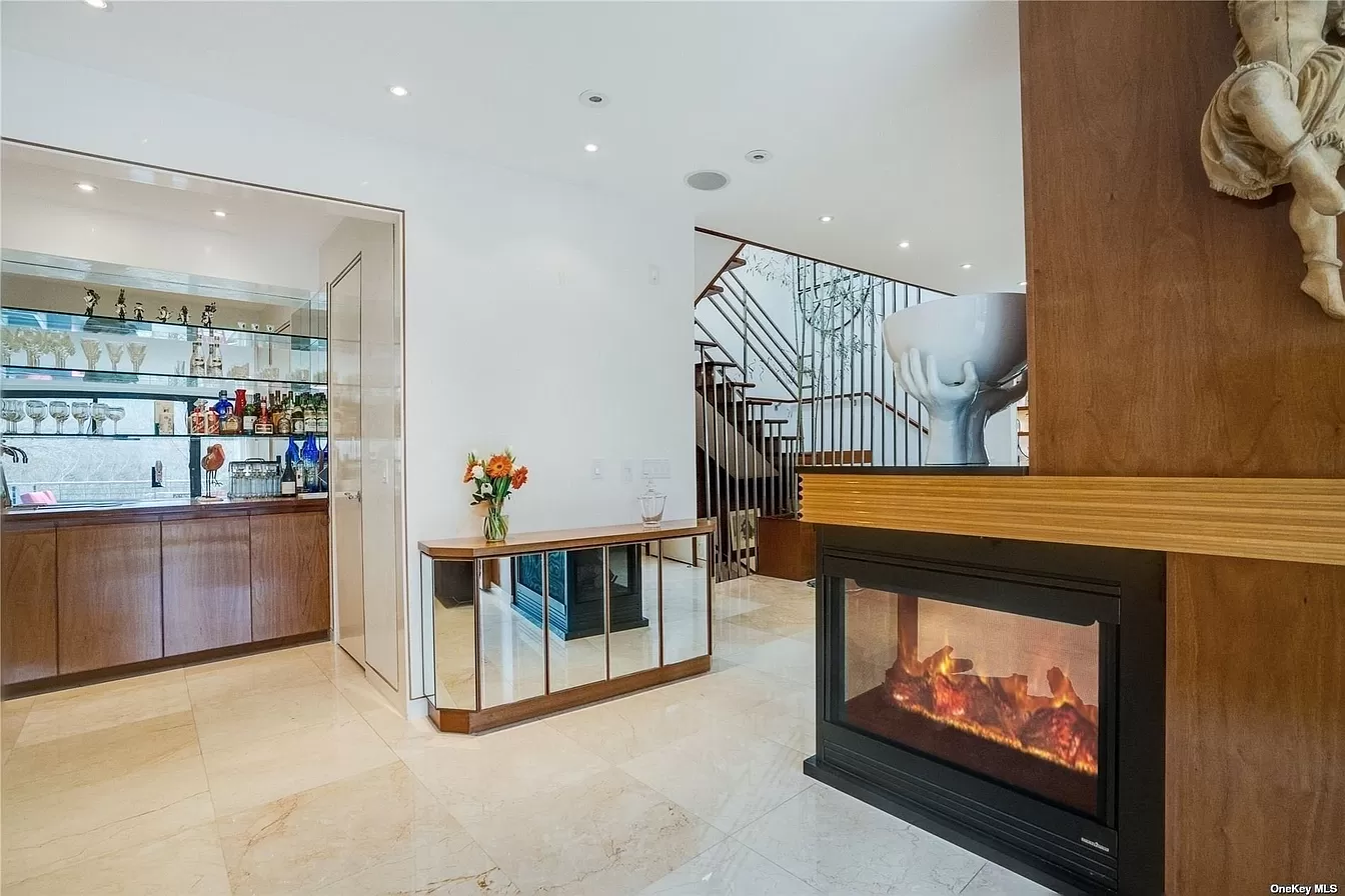 person writing in a notebook beside by an iPad, laptop, printed photos, spectacles, and a cup of coffee on a saucer